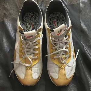 Nike White and Gold Sneakers with Iconic Swoosh